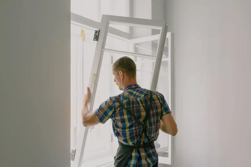 Installer lifting a window sash into an open frame