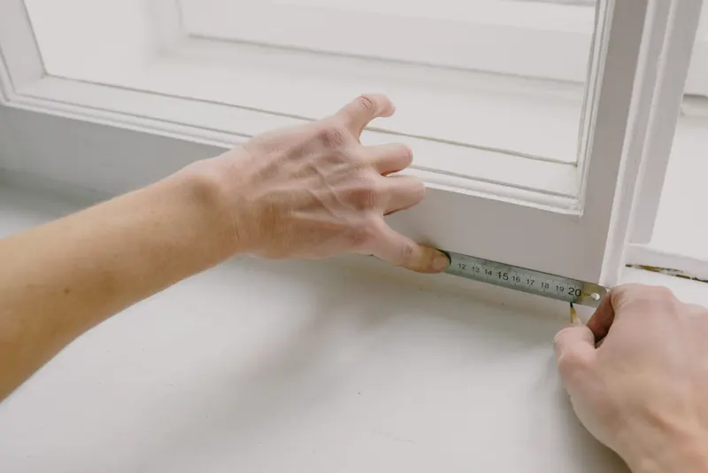 Hands measuring a window frame with a ruler